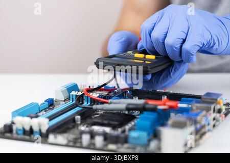 Technician in gloves grips red multimeter probe probing electric components on circuit board. Diagnostic testing in technical laboratory setting Stock Photo