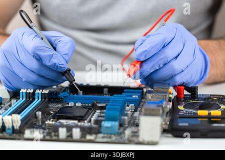 Testing motherboard with probes and multimeter, Close-up of technician using probes on computer motherboard with red multimeter during electronic diag Stock Photo