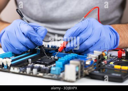 Technician in gloves grips red multimeter probe probing electric components on circuit board. Diagnostic testing in technical laboratory setting Stock Photo