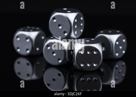five silver dice view from above on black background. Stock Photo