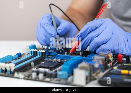 Technician under fixed and repairing computer mainboard process by used multimeter AC Voltage for analysis on computer mainboard is electronic compone Stock Photo
