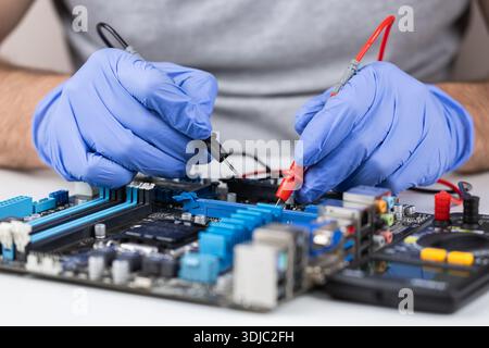 Technician under fixed and repairing computer mainboard process by used multimeter AC Voltage for analysis on computer mainboard is electronic compone Stock Photo