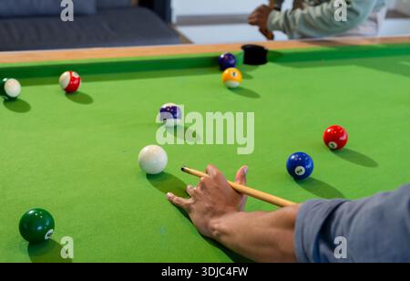 Two adults aiming with cue lining up shot on billiards table in game room, copy space Stock Photo