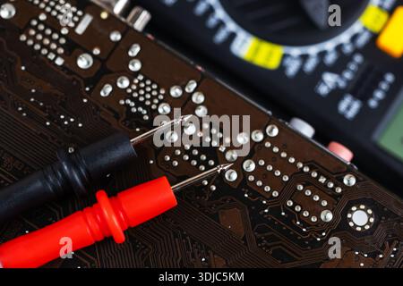 red and black multimeter probe probing electric components on circuit board. Diagnostic testing in technical laboratory setting Stock Photo