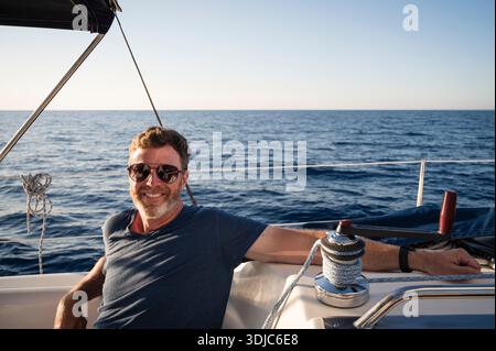 Smiling Man Relaxing on Sailboat on Calm Mediterranean Waters Stock Photo
