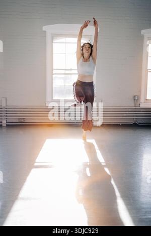 Female dancer balancing in bright sunlit studio Stock Photo