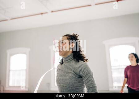 Woman joyfully exercising with rhythm ribbon indoors Stock Photo