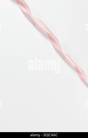 Top view of pink ribbon on white background. Shiny rolled fabric, silk and satin material. Copy space. Stock Photo