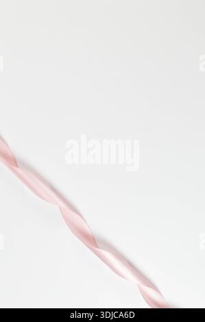 Top view of pink ribbon on white background. Shiny rolled fabric, silk and satin material. Copy space. Stock Photo