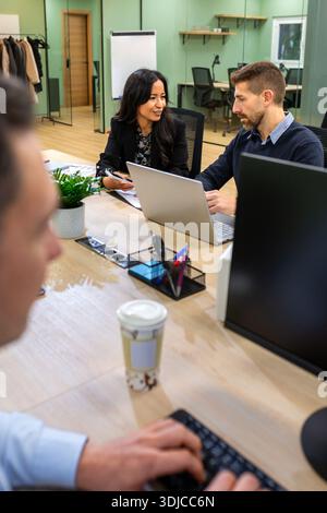 Hispanic business woman showing telephone screen to caucasian man in modern coworking office Stock Photo