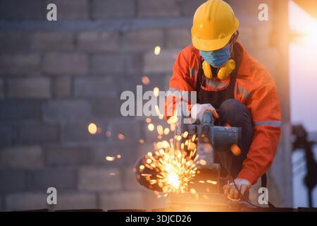 Construction working wearing protective workwear standing in a new build building using a circular saw Stock Photo