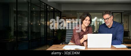 Business team of two busy professionals working on laptop discussing ai project. Stock Photo