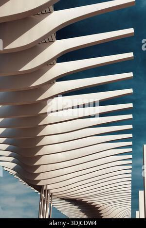 An abstract, low-angle view of a contemporary architectural structure featuring curving, horizontal concrete slats. The lines create repetitive patter Stock Photo