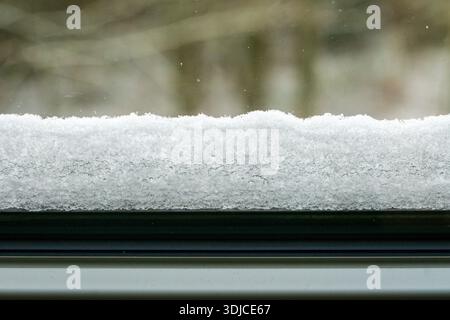 A close up view of a fresh snow layer resting on a windowsill during winter. Stock Photo