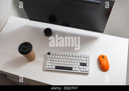 Clean modern workspace with computer monitor, keyboard, mouse and coffee cup on white desk. Home office and productivity concept. Stock Photo