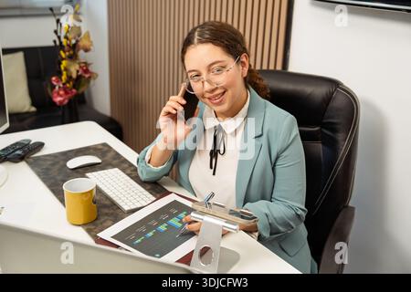 Businesswoman networking while multitasking and working at her corporate office desk Stock Photo