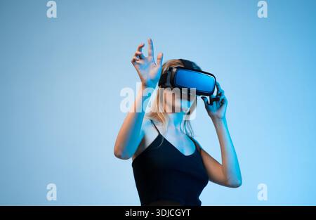 Woman adjusting virtual reality headset and interacting with digital space, immersive VR technology and future innovation Stock Photo