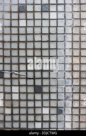 Close-up of small square mosaic tiles with worn grout and subtle color variations forming a geometric grid pattern Stock Photo