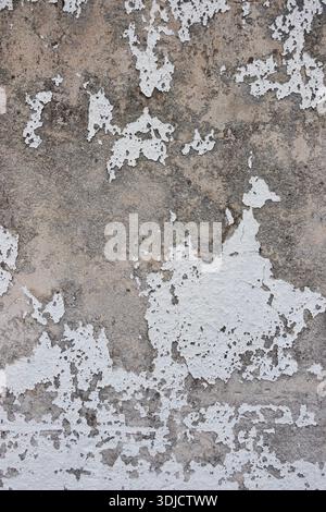 Severely weathered wall with peeling paint and exposed plaster creating a gritty, distressed texture background Stock Photo