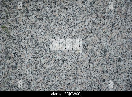 Close-up of a natural marble or granite stone surface with fine speckled texture and neutral gray tones. Detailed rock pattern. Ideal for background. Stock Photo