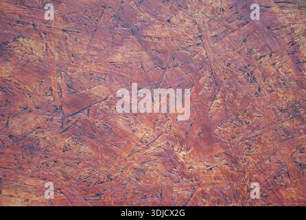 Detailed close-up DIY OSB wood panel showing rough texture and layered pattern of oriented strand wood board. Warm brown tones, background, wallpaper. Stock Photo
