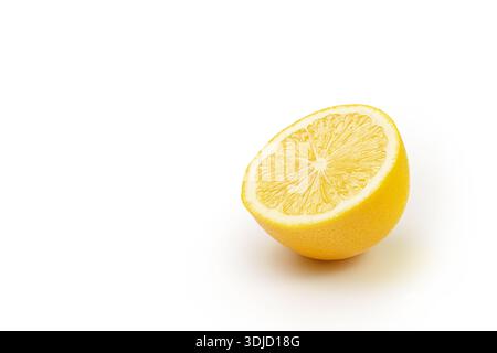 A slice of lemon is cut in half and placed on a white background. The orange is the main focus of the image, and the white background emphasizes its b Stock Photo