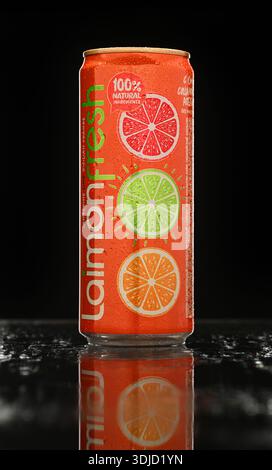 A can of laimon fresh with three oranges on it. The can is sitting on a table with a dark background Stock Photo