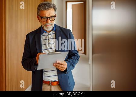 Portrait of focused male professional in eyeglasses writing on clipboard while brainstorming ideas in modern office Stock Photo