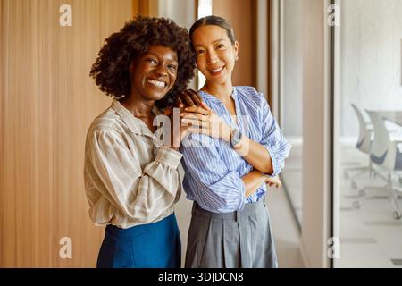 Portrait of smiling female partners standing confidently together and posing in modern office corridor Stock Photo
