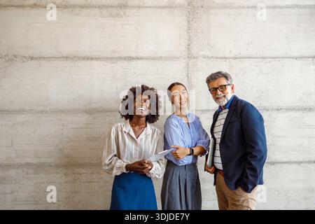 Portrait of successful team of professionals posing confidently together against wall in corporate office Stock Photo