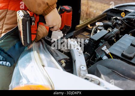 Service worker works on car metal frame using power drill in garage service residential area Stock Photo