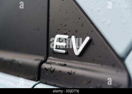 EV badge detail on electric vehicle body panel, indicating a car powered fully by electricity Stock Photo