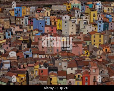 Aerial view of a vibrant tapestry of closely packed buildings with terracotta roofs and pastel-colored facades, Bosa, Sardinia, Italy. Stock Photo