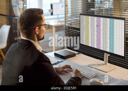 Accountant man analyzing spreadsheet data on computer monitor in modern office Stock Photo