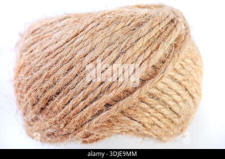 Close-up macro shot of a tightly wound ball of natural jute twine on a white background Stock Photo