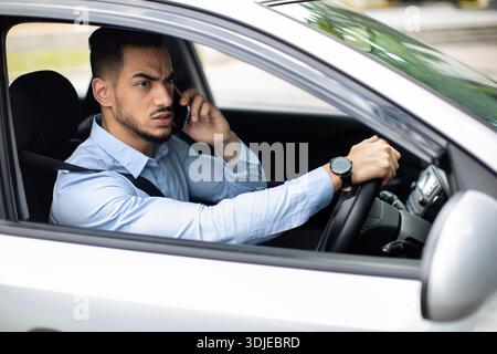 Angry arabic guy manager fighting on phone while driving auto Stock Photo