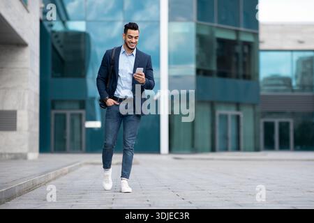 Confident arabic guy programmer with backpack walking by street Stock Photo