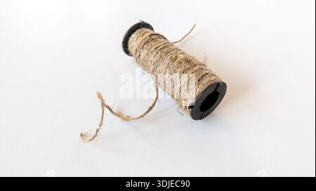 Jute twine spool with a long rope end isolated on white background. Scourge rope ball. Jute rope. Roll of twine Stock Photo