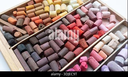 Different soft pastels sticks set in wooden case. Pink, red, yellow, brown colored sticks. Art multicolor background. Chalk pieces top view. Art paint Stock Photo