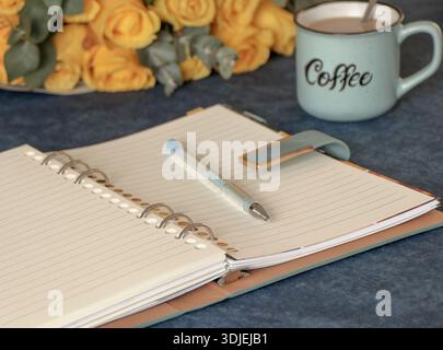 Year Planning Concept with Open Spiral Notebook, Pen, Coffee Cup on Blue Desk Stock Photo