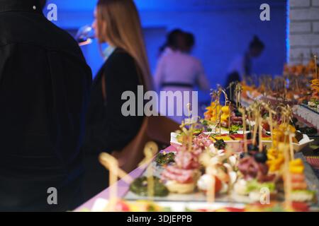 Catering service features a stunning display of snacks on a table, enhanced by evening lighting, creating a lively ambiance for guests to savor delici Stock Photo
