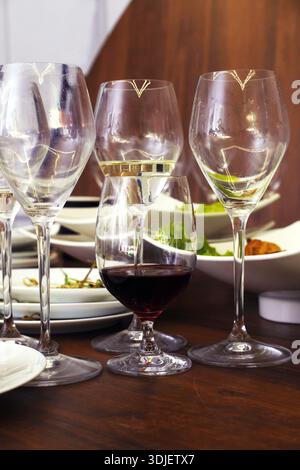 Scene of leftover food and dirty dishes after an event, with empty wine glasses and plates, capturing the essence of post-celebration cleanup and dini Stock Photo