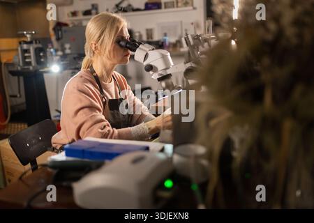 Woman examining intricate details using a microscope Stock Photo