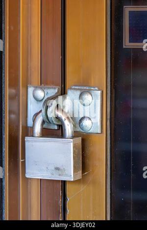 Closed retro door locked and secured with silver metal padlock Stock Photo