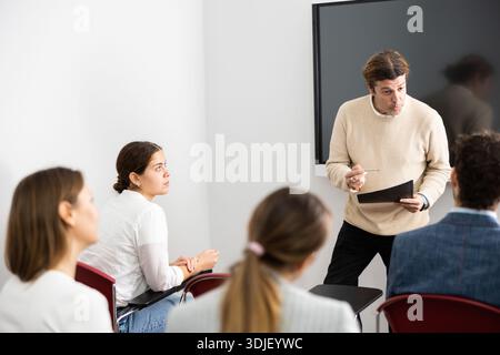 Competent male tutor teaching students in college classroom Stock Photo