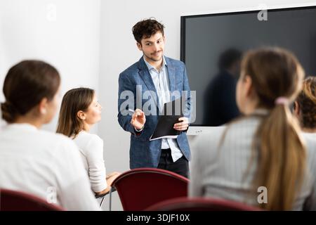 Young male professor explaining subject to classroom full of students Stock Photo