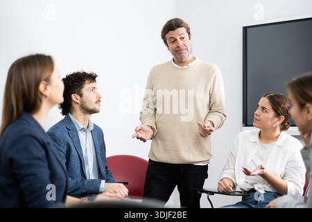 Experienced male teacher giving lecture to group of student Stock Photo