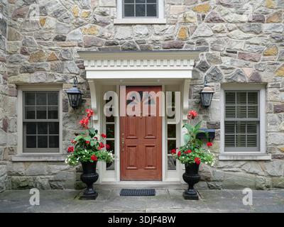Wood grain front door of old stone house, with large flower pots Stock Photo