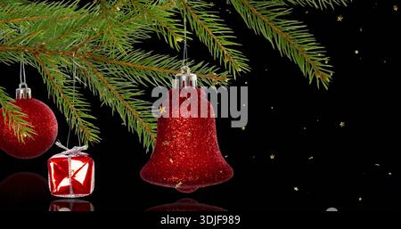 Hanging red glitter bell gleaming under fir branch, reflecting on glossy surface with red bauble Stock Photo