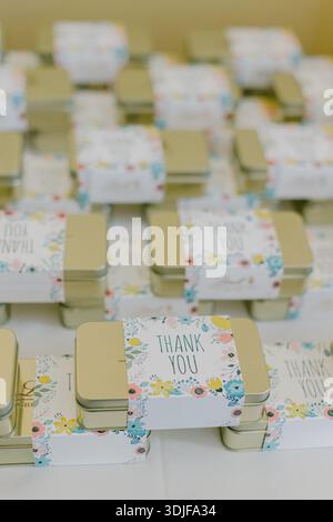 Many small metal boxes with thank you messages are placed on a table for guests at an event or celebration. Stock Photo